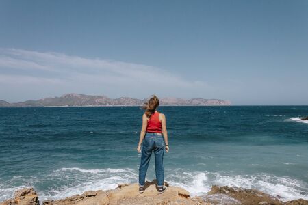 adventurous woman facing the storm of the sea, reaching the destination of the success of her adventure. Triumph concept. Loneliness concept.の写真素材