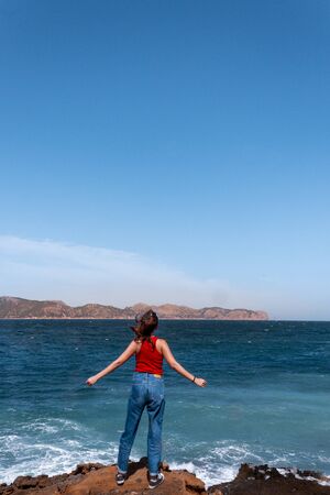 adventurous woman facing the storm of the sea, reaching the destination of the success of her adventure. Triumph concept. Loneliness concept.の写真素材