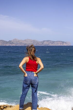 adventurous woman facing the storm of the sea, reaching the destination of the success of her adventure. Triumph concept. Loneliness concept.の写真素材