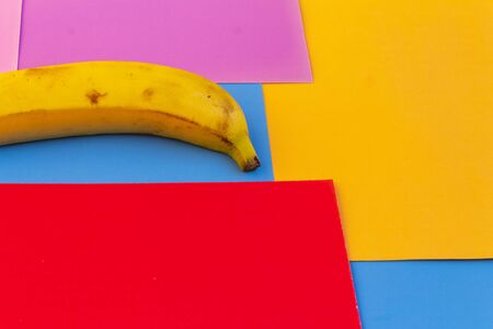 Banana in vibrant colors background, with squares and rectangular shapes in the background. Creative desing of banana product.の写真素材