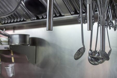 Stainless steel kitchen utensils hanging from the dryer in a professional kitchen. Preparing professional kitchen.の写真素材