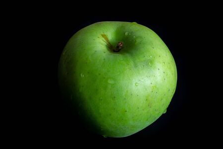 Green ripe apple with water droplets on a dark background, closeupの写真素材