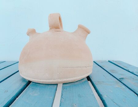 Clay jug on blue wooden table with white backgroundの写真素材