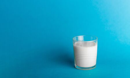 Glass of milk on blue background isolatedの写真素材