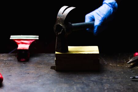 hand with blue gloves hitting with hammer wooden box, concept of repair, maintenance and crafts in a black background.の写真素材