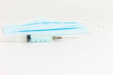 First person view of black glove holding syringe, next to protective medical mask. Vaccine concept.の写真素材