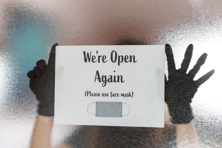 Woman putting sign back open your business protection mask in the new normal, concept back open business covidの写真素材