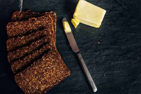 rye bread toast with butter in dark food with metal knife, healthy food concept and exquisite...