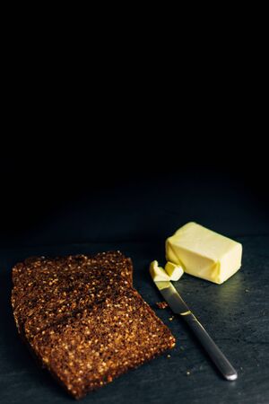 rye bread toast with butter in dark food with metal knife, healthy food concept and exquisite breakfastの写真素材