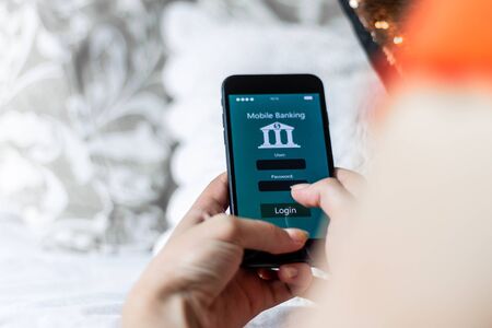 Woman using mobile banking app in her quiet room, zenithal plane, concept of using the bank whenever you want with copyspace, fintech and young people in financeの写真素材