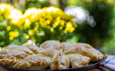 Tray of "empanadas argentinas" typical food from Argentina and Uruguay ready to eat on a tray held by hand. Concept of eating typical South American food. Pastry.の写真素材
