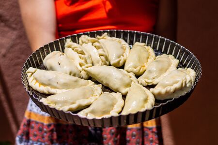 Tray of "empanadas argentinas" typical food from Argentina and Uruguay ready to eat on a tray held by hand. Concept of eating typical South American food. Pastry.の写真素材