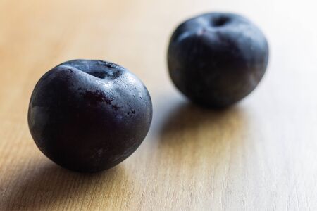 Two plums on natural wood, natural vegan food. Concept of eating fruit and digestive food to go to the toilet.の写真素材