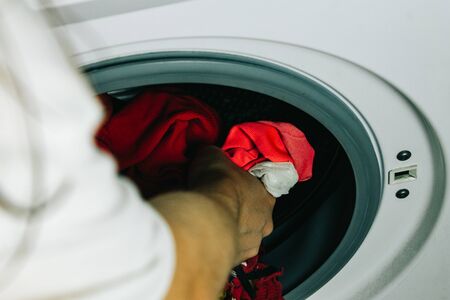 A human maid hand putting clothes inside the washing machine. Concept of doing the laundryの写真素材
