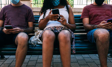 three people with mask in bank using mobile phone, social distance concept with face maskの写真素材
