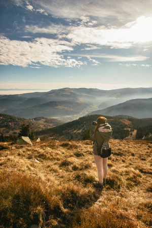 Young woman taking picture of a foggy valley from the top of Le Hohonck, Vosges mountains near Schiessrothried lake, France.の写真素材