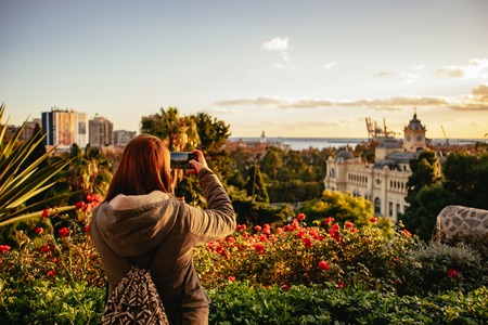 Traveling photographer shooting sunset on M?laga from a viewing point with beautiful flowers.の写真素材