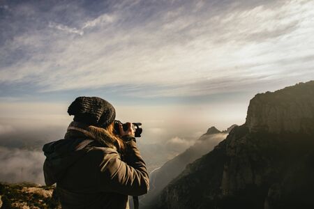 Person in warm clothing taking photographs of an atmospheric landscape in the Monestir de Montserrat Region near Barcelona Spainの写真素材