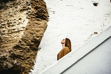 Young woman looking up at walls built into rockの写真素材