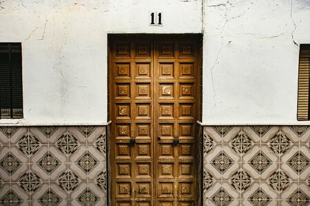 Carved wooden door and tiled wall with decorative ceramic tiles in Setenil de las Bodegas, Andalusia, Spainの写真素材