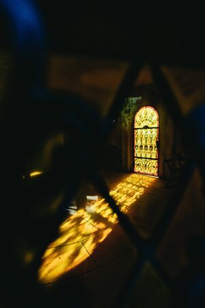 Colorful warm orange light shining through an arched window onto flagstones in Castillo de Colomares...