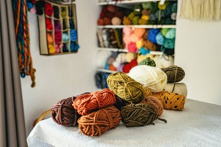 Pile of colorful balls of wool for weaving piled on a cabinet in a studio producing handicrafts