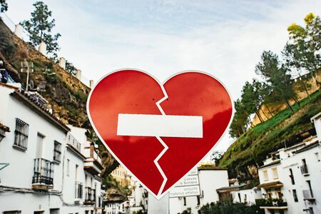 Red heart road sign in Setenil de las Bodegas, Andalusia, Spain with rows of whitewashed houses under steep cliffsの写真素材