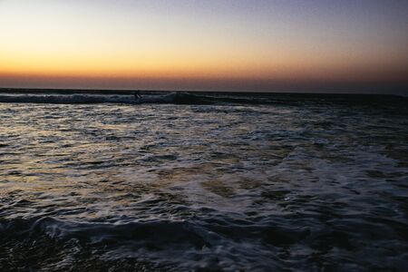 Person surfing at sunset at Sidi Kaoukiの写真素材