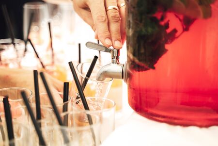 Person dispensing fruit punch into glasses