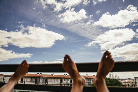 People resting feet on railing with skies aboveの写真素材