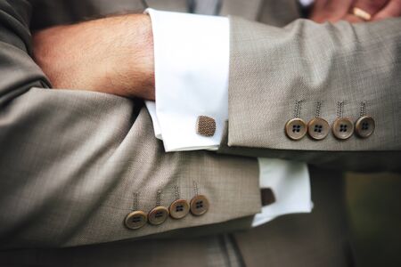 Elegant businessman in gray suit with hands on chest. Close up image of male hands. Jacket sleeve...