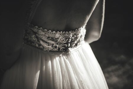 Black and white closeup of white lace wedding gown. Beautiful decoration on back of dress. Wedding day concept.の写真素材