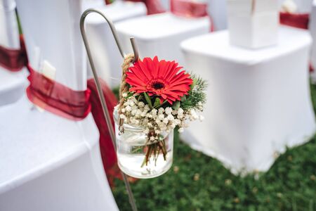 Floral wedding decoration. Red gerbera flower in glass vase. Outdoor nuptials. Wedding day concept.の写真素材