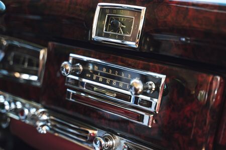 Luxury interior of old classic American car. Wooden decorated dashboard with radio and clocks.の写真素材