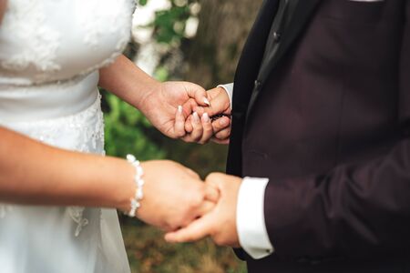 Wedding couple standing and holding hands. Closeup of hands. Wedding day concept.の写真素材