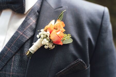 Close up of pink rose wedding boutonniere on grooms suit. Beautiful posy on lapel of jacket. Wedding day concept.の写真素材