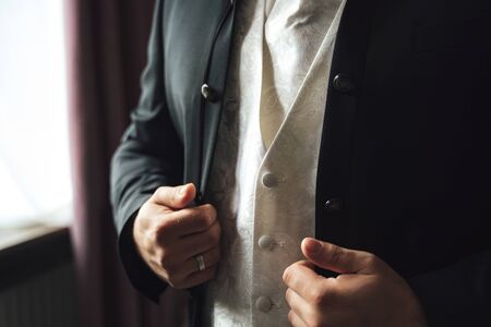 Closeup of elegant man in business suit. Black jacket and white west. Gentleman standing inside room...