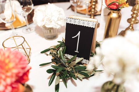 Festive table decoration. Close up of standing number of table and arrangement of glassware and dishes. Celebration, wedding, birthday concept.の写真素材