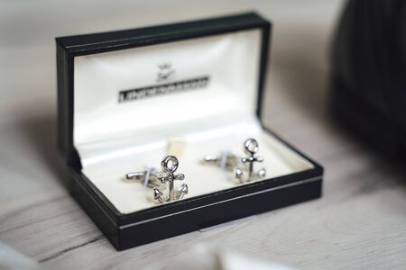 Close up of shiny anchor cufflinks in black padded box. Light background.の写真素材