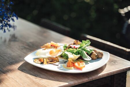 Vegetarian menu. White plate with fresh vegetable laying on wooden table. Celebration, party, birthday or wedding concept.の写真素材