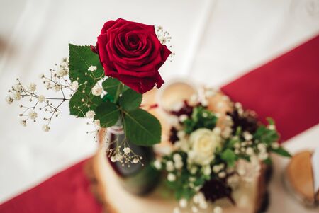Red rose close up. Flower in vase on festive table. Red and white background. Copy space.の写真素材
