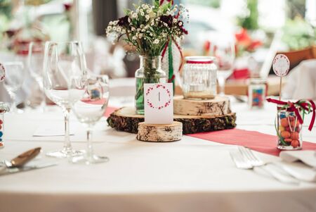 Festive table decoration. Close up of colorful flower bouquet in glass vase and arrangement of glassware. Celebration, wedding, birthday concept.の写真素材
