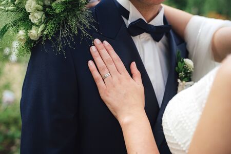 Bridesmaid helping bride to dress wedding gown. Close up of hands fastening buttons on lace wedding dress. Wedding day concept.の写真素材