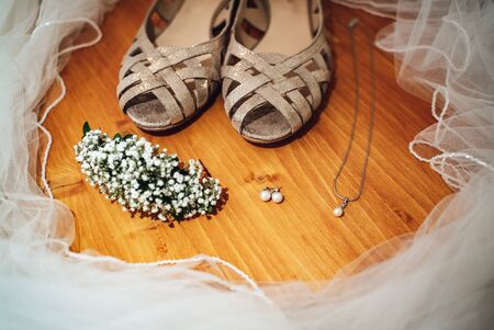 Brides accessories: shoes, earrings, jewelry and veil on wooden background. Wedding day concept.の写真素材