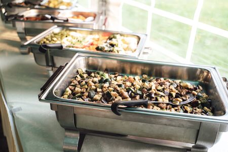 Row of stainless hotel pans on food warmers. Warm vegetable as side dishes. Self-service buffet...