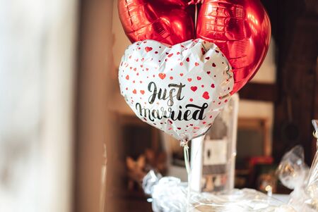 Romantic group of inflated plastic balloon in heart shape. One white piece with red hearts and lettering "Just married" and two red color.の写真素材