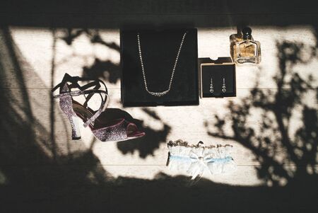 Womenâ€™s shoe, jewelry, bottle of perfume and garter flat lay composition. Wooden background...