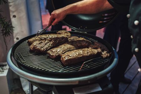 Several pieces of meat on grill, preparation of meal. Man taking care of meal. Celebration, BBQ, party conceptの写真素材
