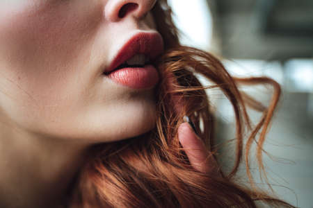 Closeup of partly opened full lips with distinctive red lipstick. Young pretty female model face detail.の写真素材