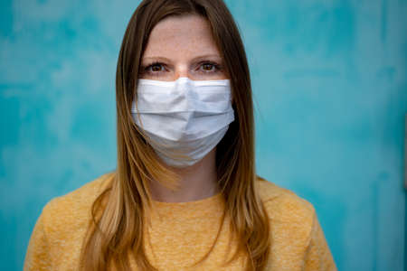 Portrait of caucasian woman wearing white disposal face mask to avoid Covid-19 disease. Corona virus pandemic protection concept.の写真素材